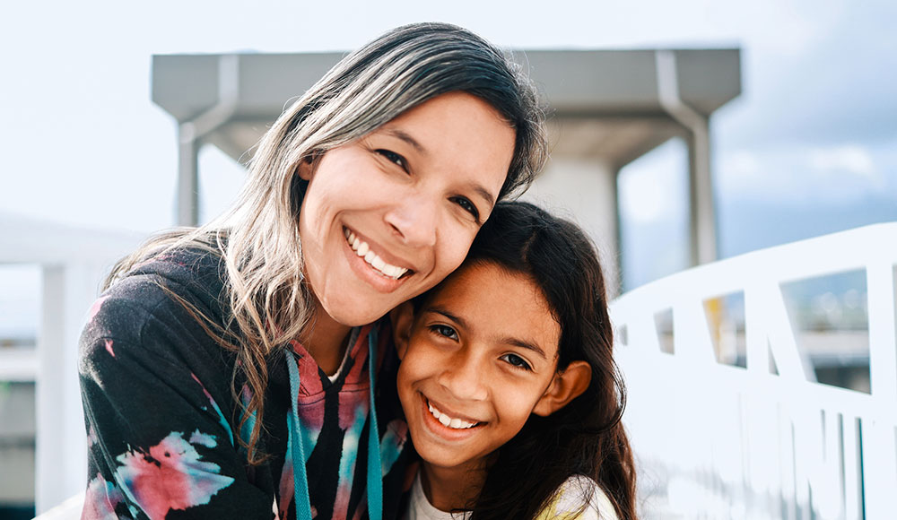 Image of woman and young girl hugging and smiling